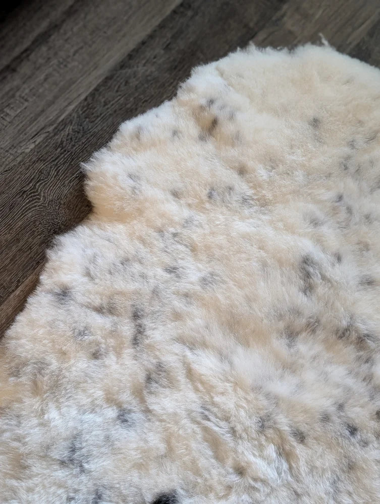 Cream icelandic sheepskin rug with soft short wool and dark gray speckles perfect for cozy decor