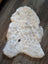 Cream-colored icelandic sheepskin rug with natural black and gray speckles made of short wool, 45 by 31 inches