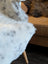 White and gray speckled faux fur throw blanket draped over chair made from short wool icelandic sheepskin