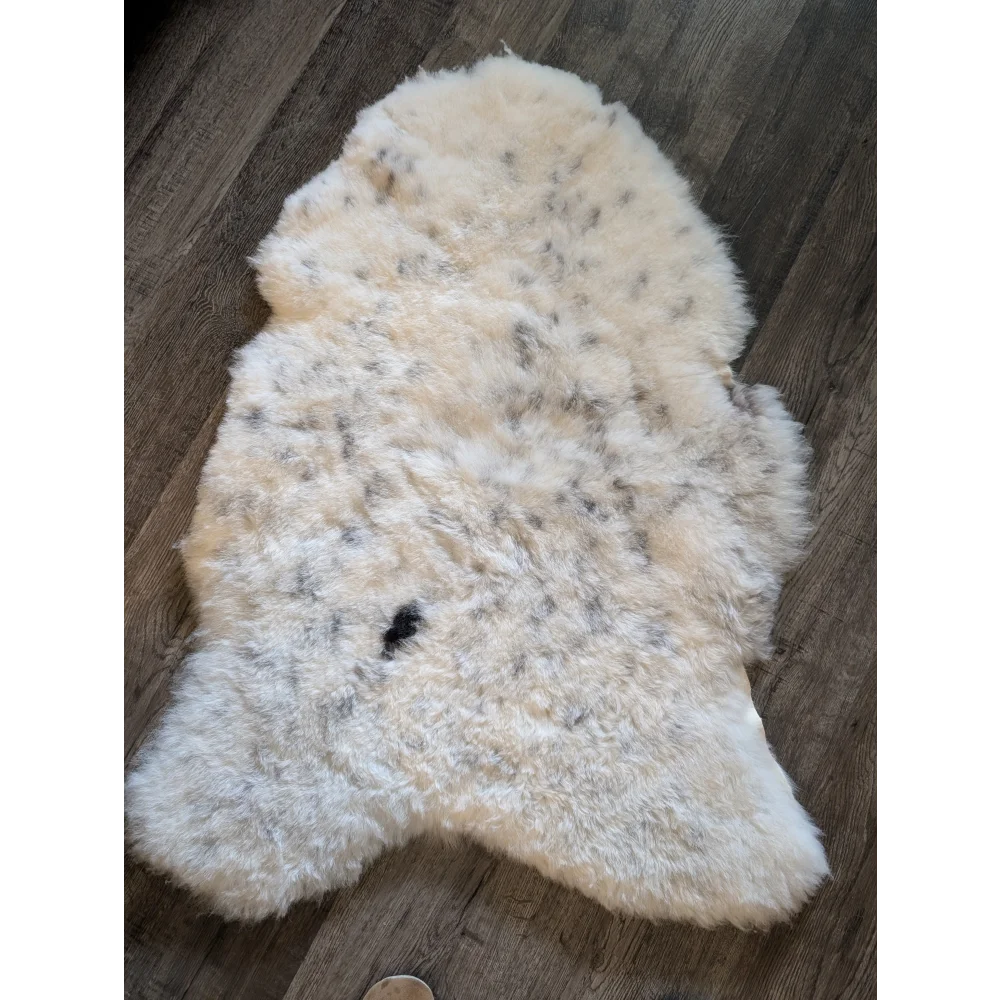 Cream-colored icelandic sheepskin rug with soft short wool and dark speckles in large 45 by 31 size