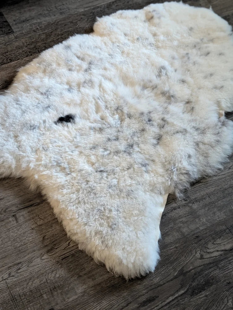 A plush off-white icelandic sheepskin rug with soft short wool and subtle gray speckles in large size 45 x 31 inches