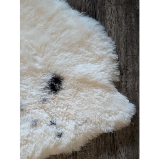 Cream icelandic sheepskin rug in short wool with fluffy texture and dark speckles 41 by 29 inches medium spot