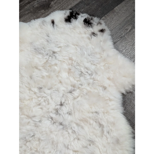 Large soft spotted icelandic sheepskin rug with white curly fur and black patches perfect for cozy decor