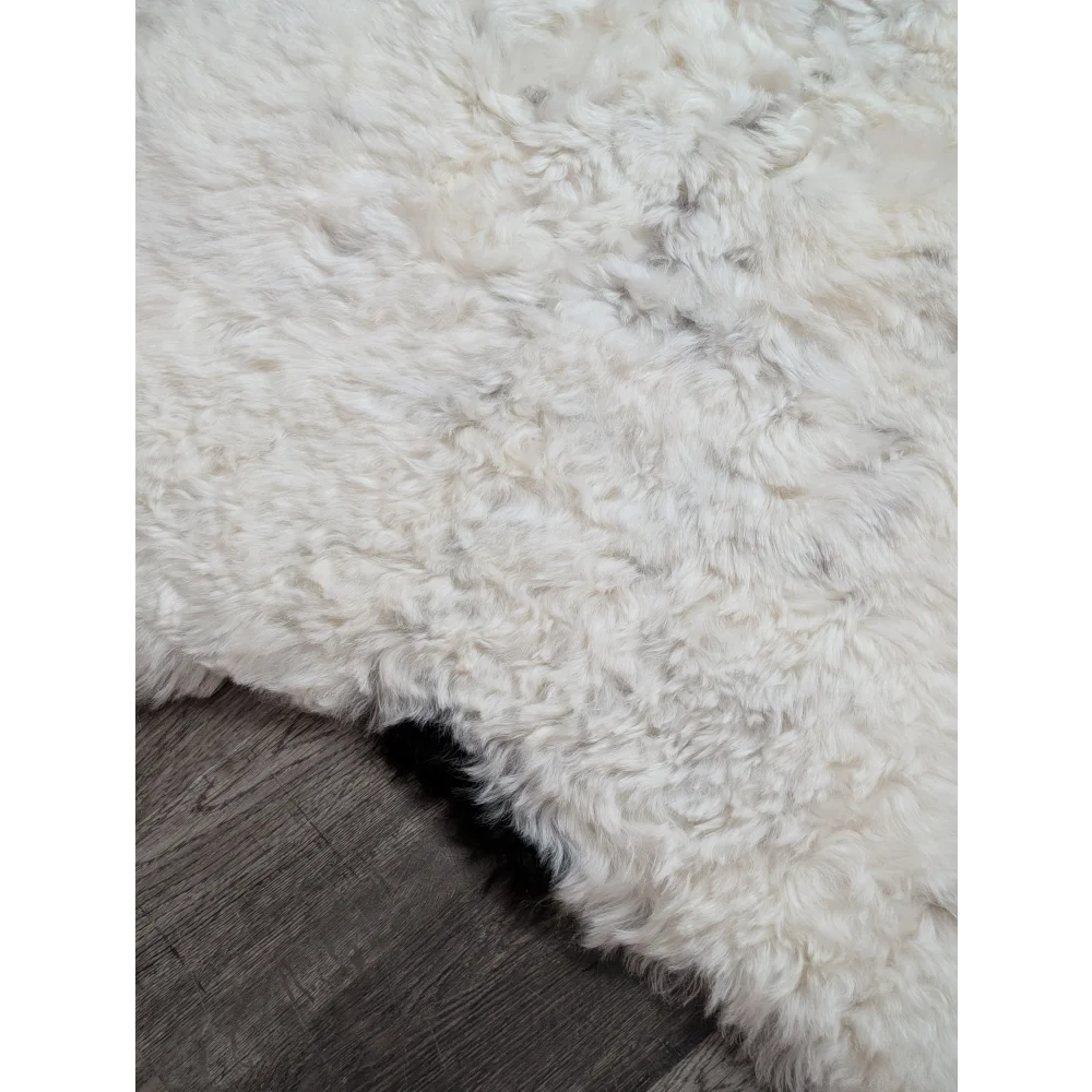A plush off-white medium spotted icelandic sheepskin rug with soft curly texture and natural edges