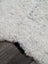 A plush off-white medium spotted icelandic sheepskin rug with soft curly texture and natural edges