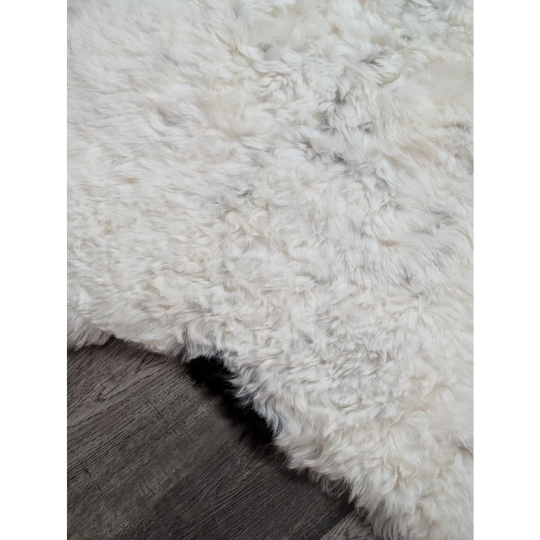 A plush off-white medium spotted icelandic sheepskin rug with soft curly texture and natural edges