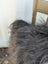 A thick shaggy gray blanket made from natural black icelandic sheepskin long wool perfect for cozy sewing machine projects