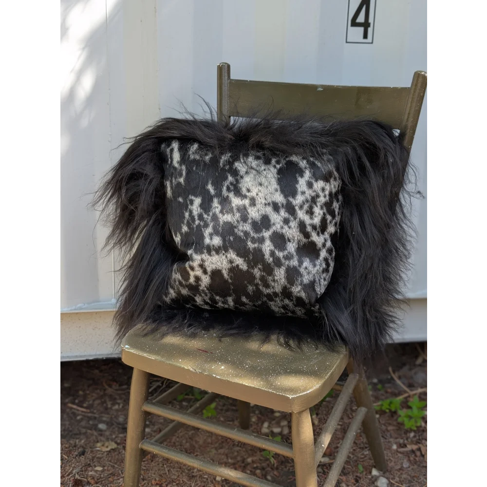 Black and white spotted cowhide pillow with long wool icelandic sheepskin trim perfect for sewing machines use
