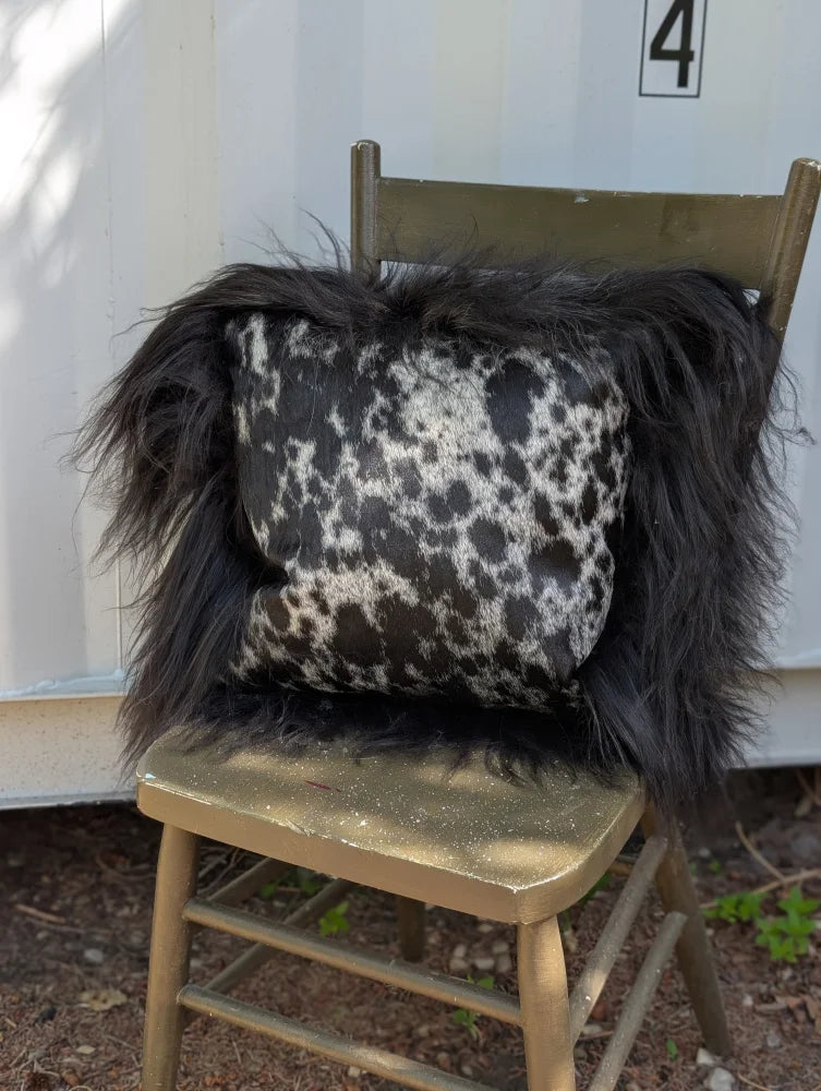 Black and white spotted cowhide pillow with long wool icelandic sheepskin trim perfect for sewing machines use