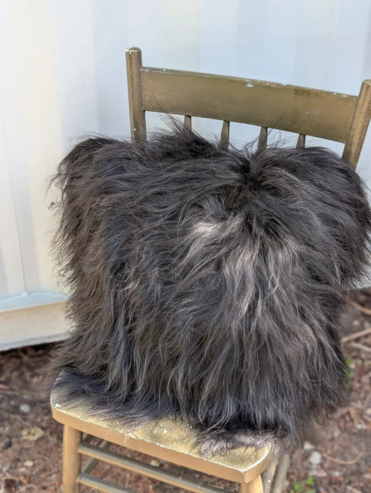 A plush spotted cowhide and natural black icelandic throw pillow with long wool icelandic sheepskin texture