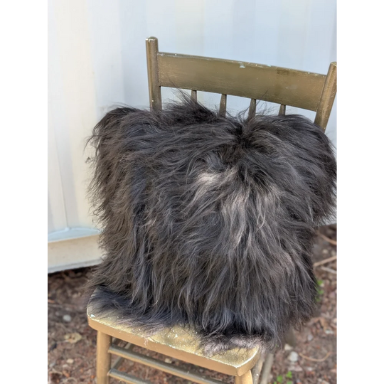 A plush spotted cowhide and natural black icelandic throw pillow with long wool icelandic sheepskin texture