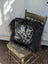 Spotted cowhide pillow with black and white spots and long black icelandic sheepskin wool trim perfect for cozy decor
