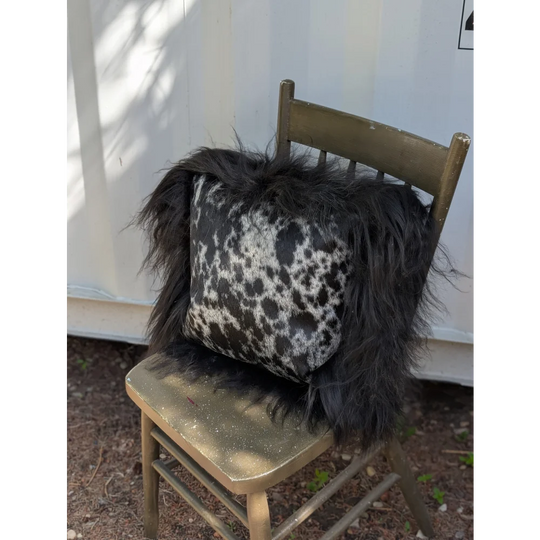 Spotted cowhide pillow with black and white spots and long black icelandic sheepskin wool trim perfect for cozy decor
