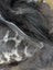 A silver-toned zipper runs along the edge of dark spotted cowhide with natural black icelandic sheepskin markings