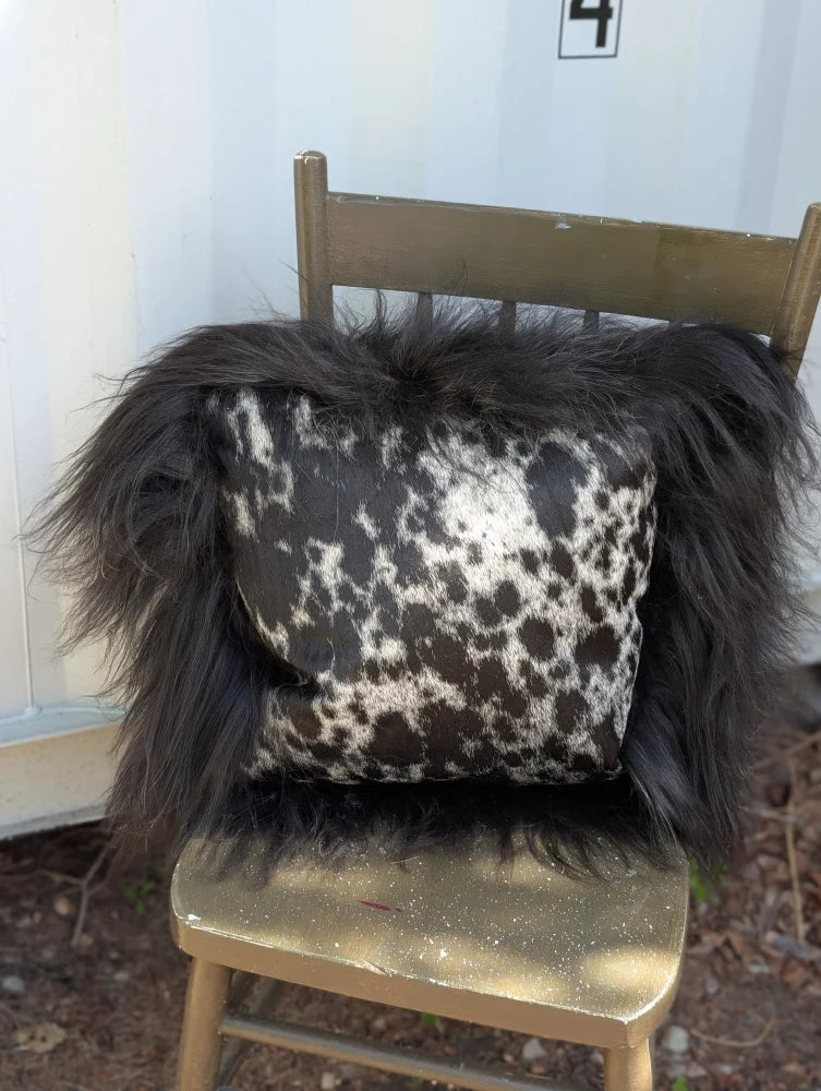 Black and white spotted cowhide pillow with fluffy natural black icelandic sheepskin long wool trim