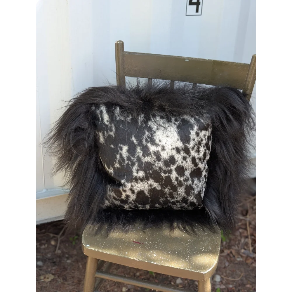 Black and white spotted cowhide pillow with fluffy natural black icelandic sheepskin long wool trim