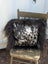 Black and white spotted cowhide pillow with fluffy natural black icelandic sheepskin long wool trim