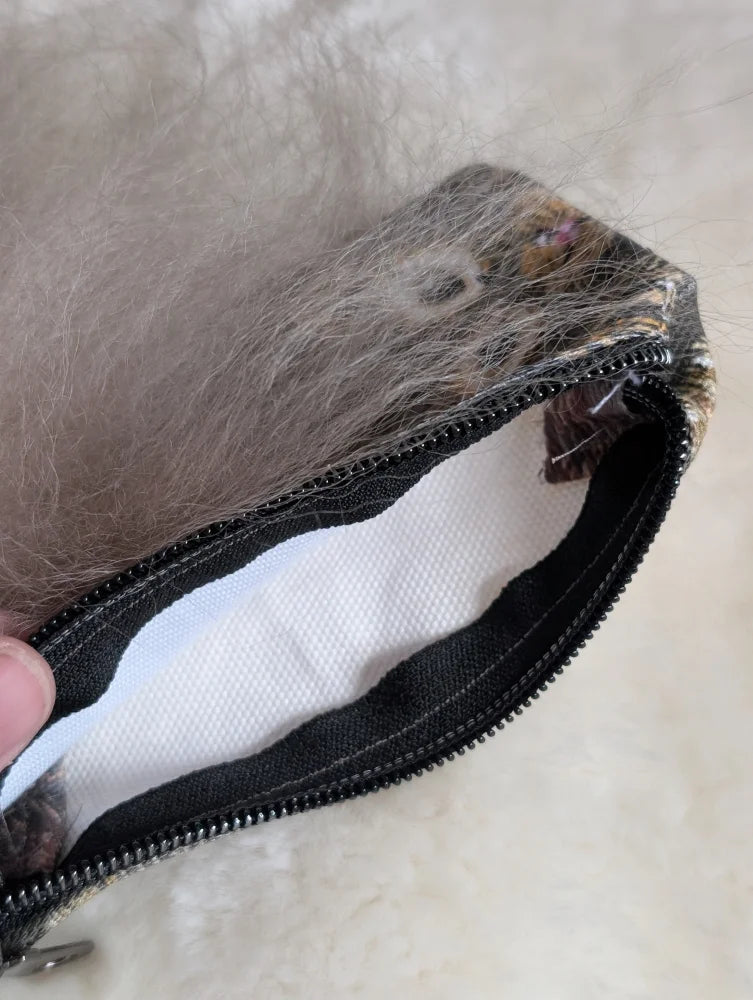 A gray cotton canvas squirrel coin purse with a sheepskin tail and faux fur lining with a black zipper