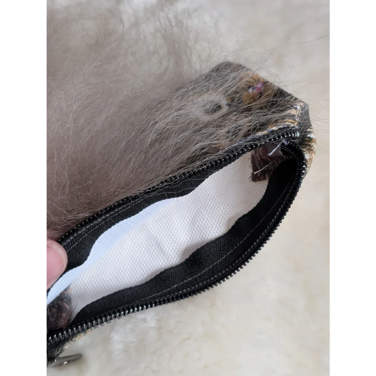 A gray cotton canvas squirrel coin purse with a sheepskin tail and faux fur lining with a black zipper