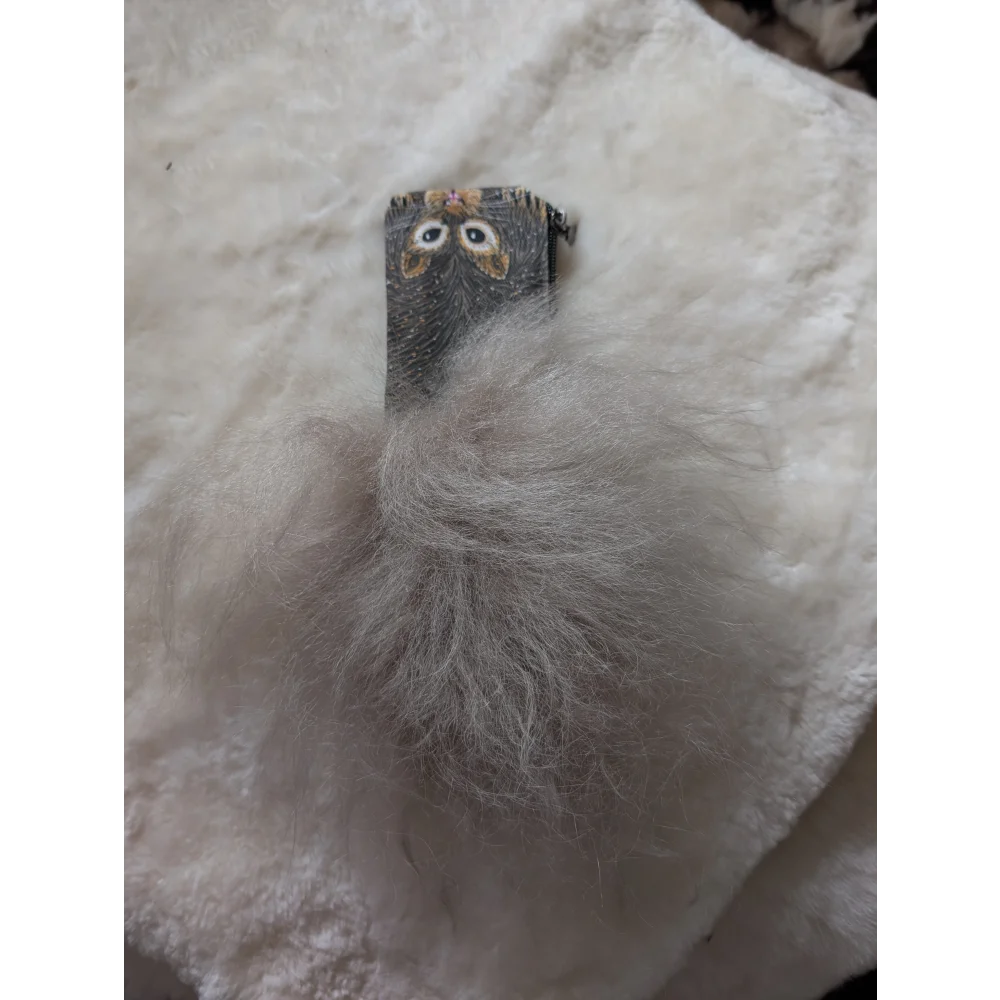 Gray fuzzy pom-pom keychain with small owl clip attached to a cotton canvas squirrel coin purse with sheepskin tail