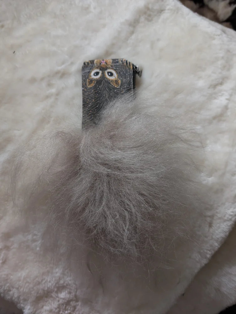 Gray fuzzy pom-pom keychain with small owl clip attached to a cotton canvas squirrel coin purse with sheepskin tail