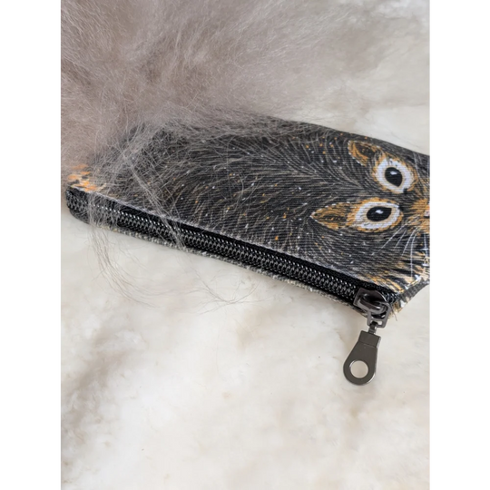 Black cotton canvas coin purse with embroidered squirrel face and sheepskin tail resting on soft gray fur