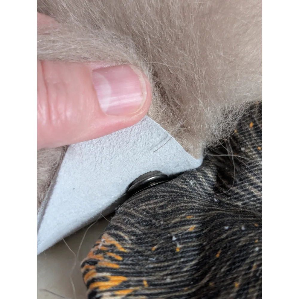 A light gray leather patch with black button on a cotton canvas squirrel coin purse with sheepskin tail fur