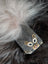 A small black cotton canvas coin purse with a cat face illustration and a fluffy sheepskin tail charm
