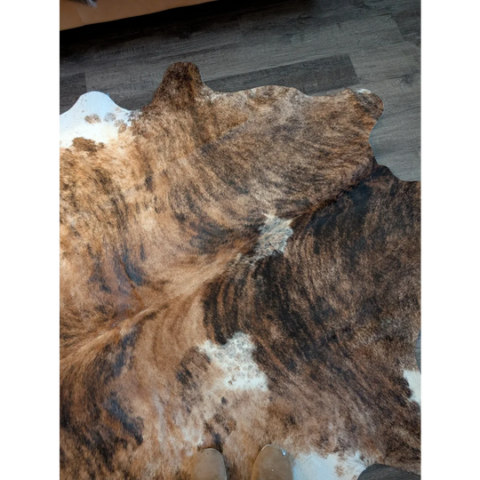 Large brown and white cowhide rug with natural irregular edges featuring unique characteristics perfect for beautiful rugs