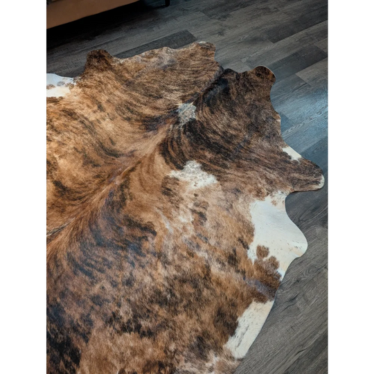 Large cowhide rug with brown and white natural irregular edges showcasing unique characteristics for beautiful rugs