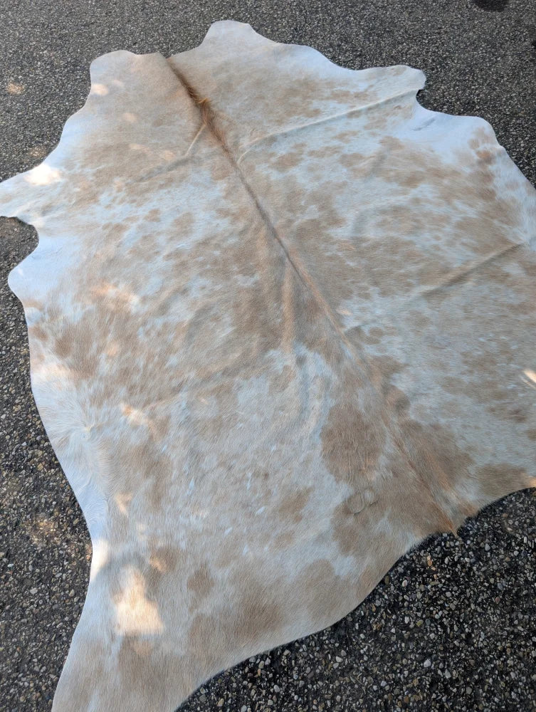 Large cowhide rug in natural white and tan with soft textured surface perfect for adding rustic charm to any space