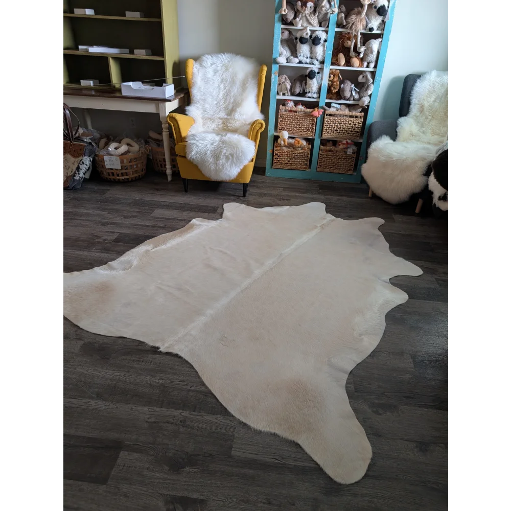 Cream-colored large cowhide rug with soft fluffy texture and unique irregular edges perfect for beautiful rugs decor