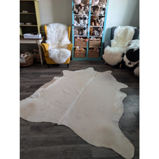 Cream-colored large cowhide rug with pale beige tones and unique characteristics in a soft fluffy texture