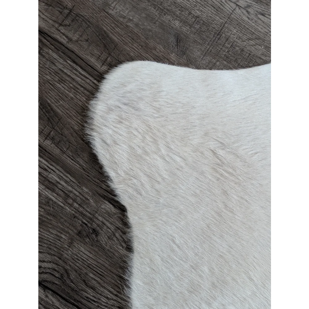 A large cowhide rug in white ivory with soft off-white faux fur and beautiful natural-looking edges for unique characteristics