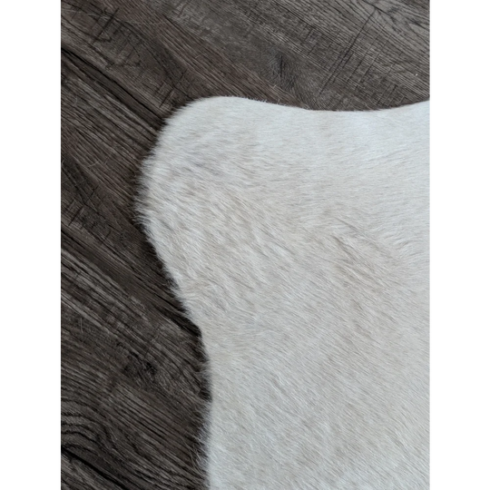 A large cowhide rug in white ivory with soft off-white faux fur and beautiful natural-looking edges for unique characteristics
