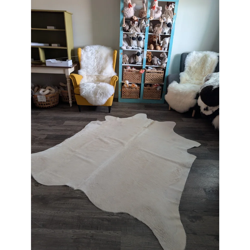 Cream-colored large cowhide rug with unique characteristics and soft textured surface perfect for beautiful rugs collection