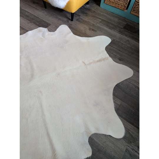 A large cowhide rug in white ivory with beautiful rugs and unique characteristics featuring soft texture and natural edges