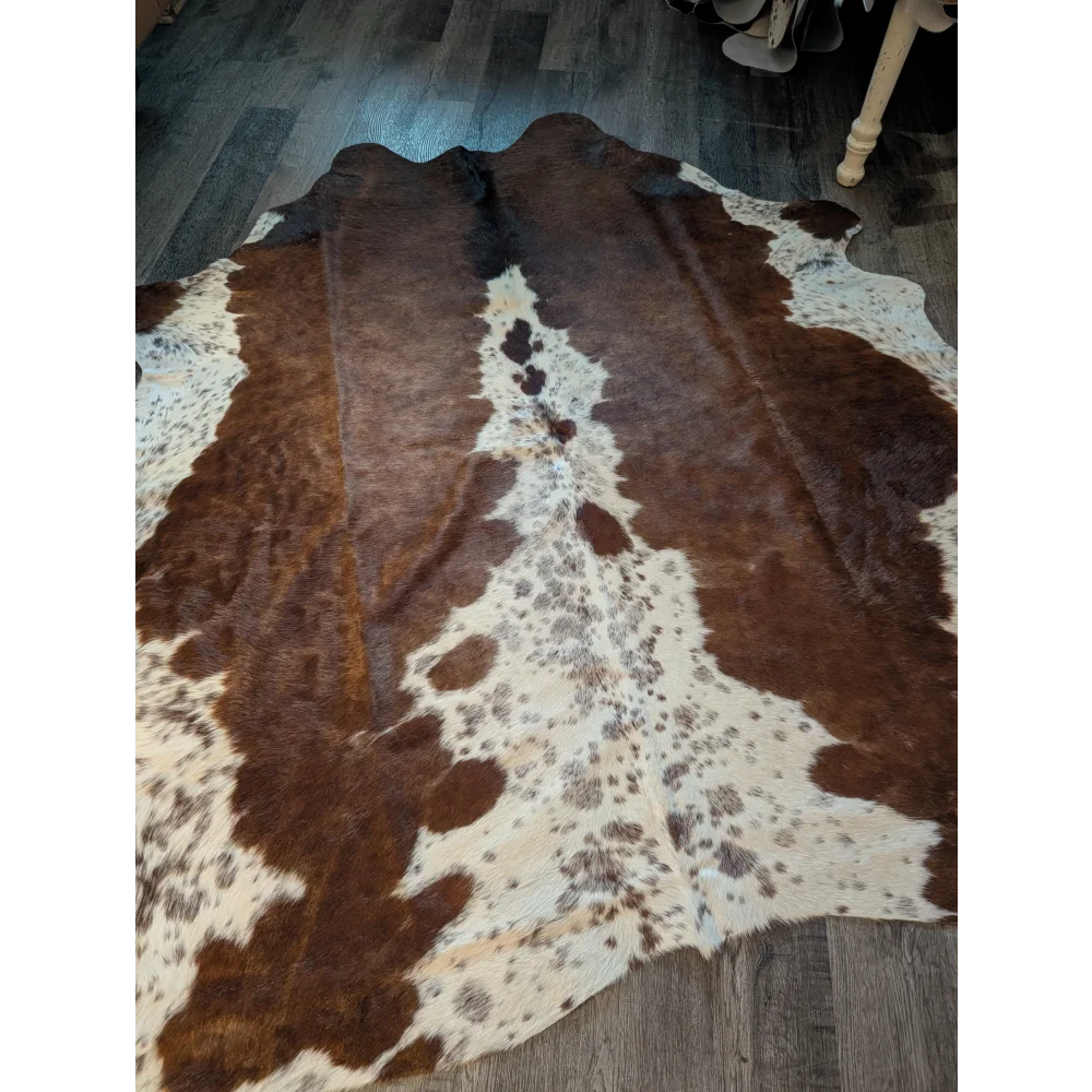 Large brown and white cowhide rug with natural fur texture featuring unique characteristics and beautiful rugs style