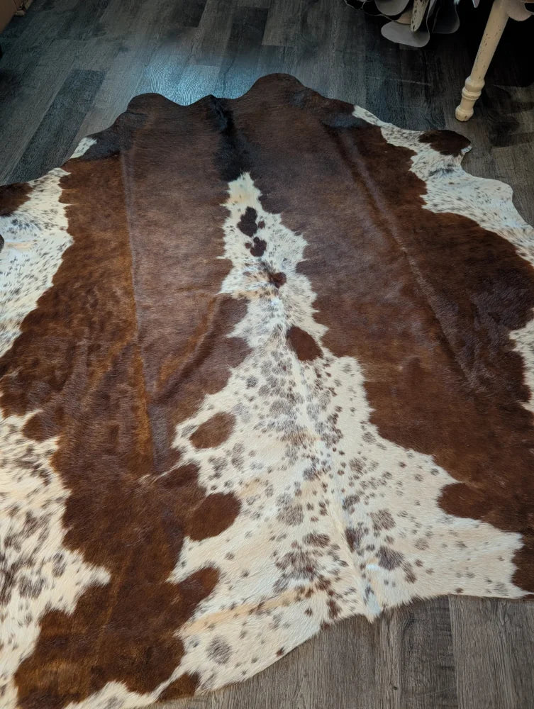 Large brown and white cowhide rug with natural fur texture featuring unique characteristics and beautiful rugs style