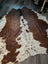 Large brown and white cowhide rug with natural fur texture featuring unique characteristics and beautiful rugs style