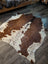 Large cowhide rug in brown and white with natural irregular edges showcasing unique characteristics and beautiful rugs style