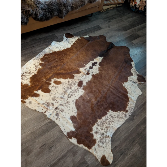 Large cowhide rug in brown and white with natural irregular edges showcasing unique characteristics and beautiful rugs style