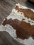 Large brown and white cowhide rug with natural fur texture featuring unique characteristics for beautiful rugs