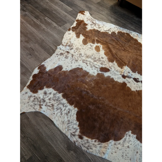 Large brown and white cowhide rug with natural fur texture featuring unique characteristics for beautiful rugs