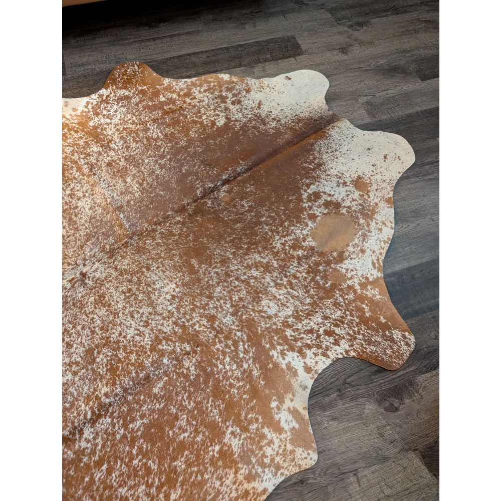 Large cowhide rug with brown and white speckles and natural irregular edges showcasing unique characteristics