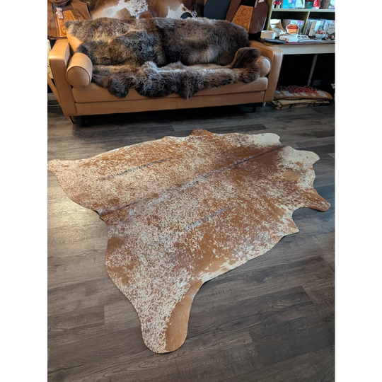 Large brown and white speckled cowhide rug with natural edges showcasing unique characteristics for beautiful rugs