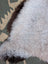 A soft fluffy white icelandic sheepskin rug with long wool and a dark brown border by angus oliver