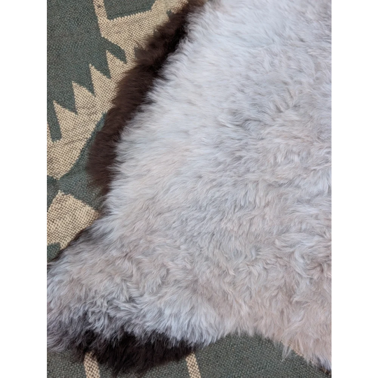 A soft fluffy white icelandic sheepskin rug with long wool and a dark brown border by angus oliver