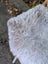 A large 43 x 35 gray long wool icelandic sheepskin rug draped over a wicker chair for cozy decor