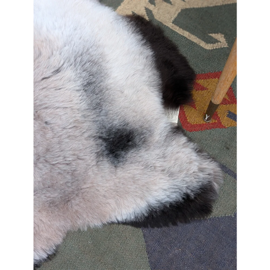 A plush white and black long wool icelandic sheepskin rug with natural texture by angus oliver measuring 43.5 by 33 inches
